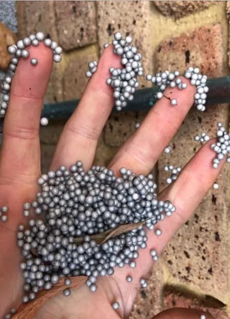 Polystyrene insulation beads stuck to a hand after cavity removal