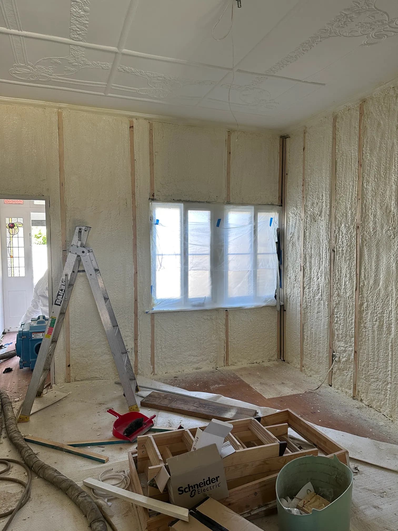 Room under renovation with spray foam insulation applied between wall studs