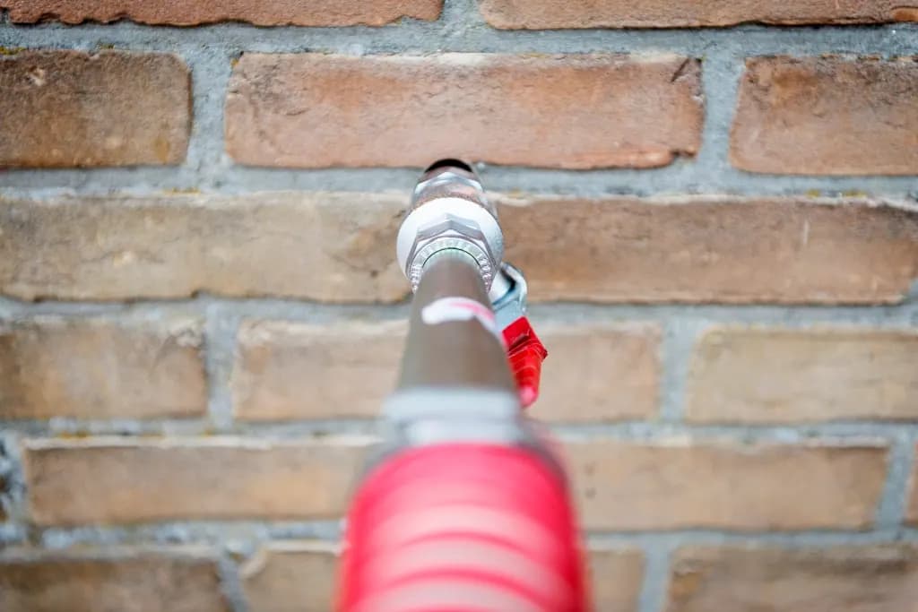 Injection nozzle inserted into the mortar joint of a brick wall